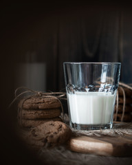 Chocolate chip cookies and milk on wooden background with vignette