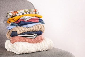 Bunch of clothing, knitted warm pastel color sweaters, different shirts and pants folded in stack...