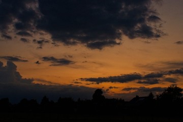 orange burning sky with silhouette of trees and houses