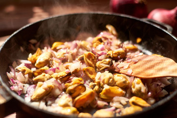 Spaghetti, pasta with mussels, tomatoes, onions and cream sauce in a pan.