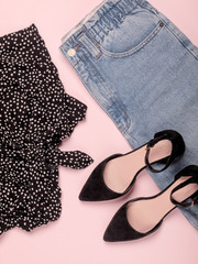 Woman's fashion and accessories like mom jeans, crop top, glasses and black heels isolated on pastel pink background. Flat lay. Top view. Copy space