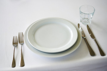 Served long white table with plates and cutlery. Preparing for the banquet, celebration.