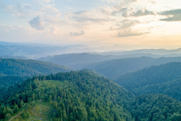 Obraz premium Sunset in the mountains. Forests and white clouds in the sky_1