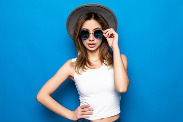 Fashion happy pretty smiling woman wearing a hat and sunglasses over colorful blue background