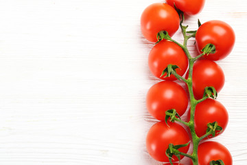 Branch of juicy organic red cherry tomatoes arranged in row on isolated white background. Polished vegetables. Clean eating concept. Vegetarian diet. Copy space, flat lay, top view.