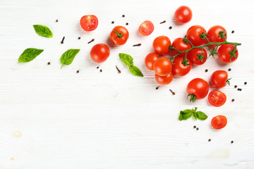 Bunch of juicy organic red cherry tomatoes arranged with green basil leaves on isolated white...