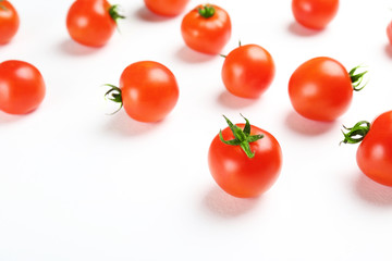 Bunch of juicy organic red cherry tomatoes scattered on isolated white background. Polished vegetables. Clean eating concept. Vegetarian diet. Copy space, flat lay, top view.