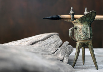 Chinese calligraphy brush and ink well on an old wood table with a driftwood study. Contemplative...