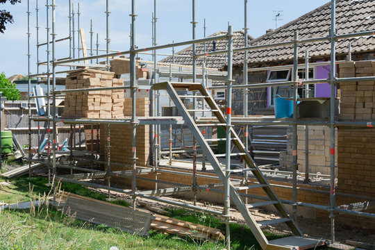 Renovation projects. Building of extension of the existing house, unfinished brick walls, block work, insulation, stacks of materials on scaffoliding, selective focus