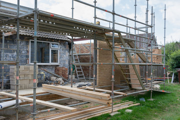 Renovation projects. Building of extension of the existing house, unfinished brick walls, block work, insulation, stacks of materials on scaffoliding, selective focus