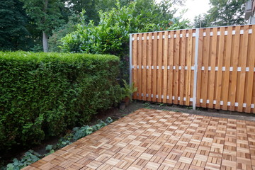Wooden partition and wooden tiles, two white garden chairs and a round table on the, with ivy and...