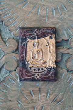 Buddha plaque on ornately carved wood. Still Life Photography.