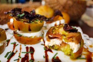 Selective Focus of Organic Caprese Salad Stacks with Heirloom tomatoes, fresh mozzarella and purple basil drizzled with balsamic reduction on white platter
