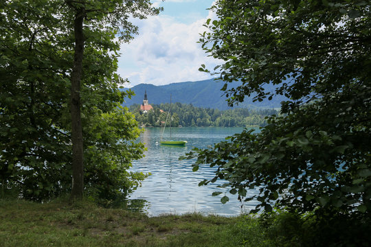 Lake Bled Slovenia. Beautiful mountain lake in summer with small Church on an island with castle on cliff and european alps in the background.