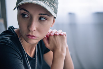 depressed woman in military uniform and cap at home with copy space