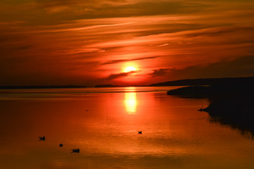 Orange sun sets in the dark water
