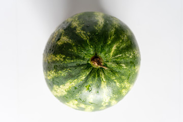 A big ripe juicy tasty green watermelon  on the white kitchen table. Top view