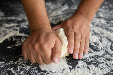 chef cooks pizza dough, strong male hands knead raw ingredients