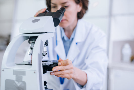 Female scientist works in the lab with the microscope shot in the close up.