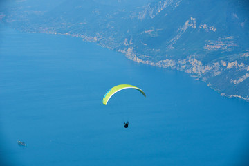 Paraglider flying over the Garda Lake (Lago di Garda or Lago Benaco), Panorama of the gorgeous Garda lake surrounded by mountains. Paragliding is very popular sport in Monte Baldo. Malcesine, Italy