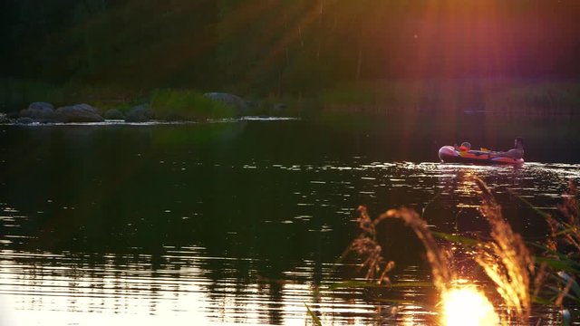 Long shot of Dad with Daughter enjoying Rubber boat ride in colorful sunset