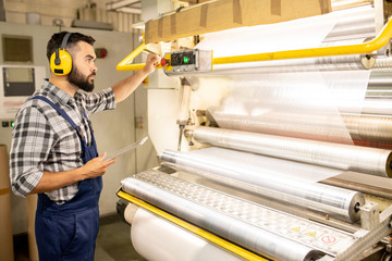 Serious young engineer of chemical production factory taking control of machine