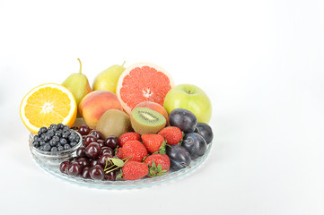 Acceptable fruits for diabetes. In a plate are orange, grapefruit, cherry, plum, pears, peaches, apple, plum, blueberries, kiwi. White background. Close-up. Free space for text.