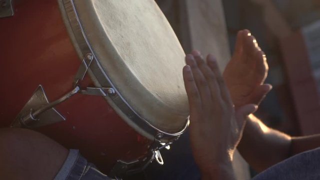 closeup of hands playing drums with a bongo