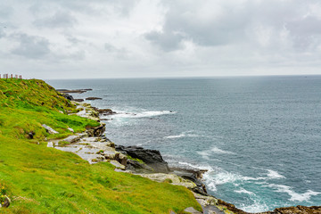 Fototapeta na wymiar Beautiful view of grass green, limestone rocks and the sea in the coastal walk route from Doolin to the Cliffs of Moher, geosites and geopark, Wild Atlantic Way, spring day in county Clare in Ireland
