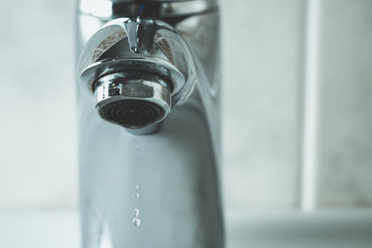 water drop dripping from the tap and water shortage