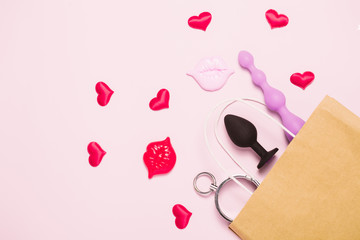 Adult sex toys and accessories purchases on pink background. Anal dildo, butt plug in paper bag....