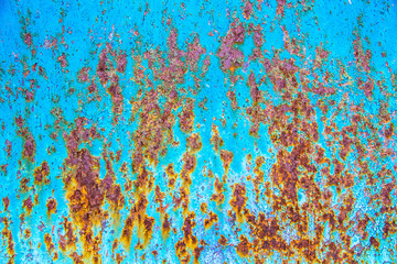 Texture of an old metal blue wall with rust, scratches, cracks, smudges and peeling paint.