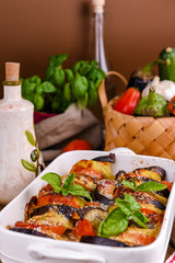 Traditional italian food. Eggplant and tomatoes with parmesan. Baked summer wax with sauce, cheese and basil. Healthy lunch for the family.