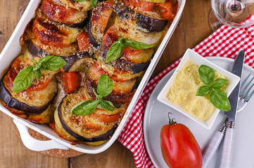 Traditional italian food. Baked eggplant, tomatoes with sauce, parmesan and basil. Rustic food for...