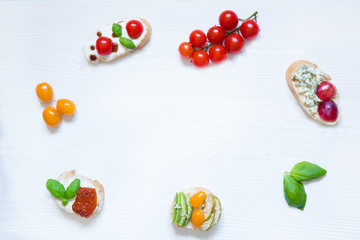 Fototapeta na wymiar Different kinds of appetizer, bruschetta with tomatoes, avocado and cheese on white table background. Space for text, copy space. 