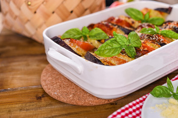 Traditional italian food. Baked eggplant, tomatoes with sauce, parmesan and basil. Rustic food for a healthy diet. Vegetables for lunch.