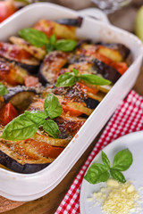 Traditional italian food. Baked eggplant, tomatoes with sauce, parmesan and basil. Rustic food for a healthy diet. Vegetables for lunch.