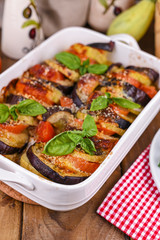 Traditional italian food. Eggplant and tomatoes with parmesan. Baked summer wax with sauce, cheese and basil. Healthy lunch for the family.