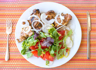 Top view of healthy meal, plate full of chicken meat and fresh salad with tomato, paprika, onions and arugula