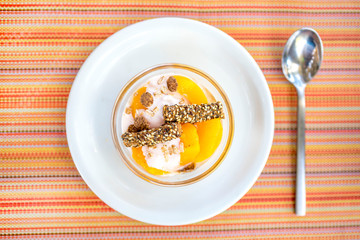 Top view of plate with apricot compote with vanilla cream, oats flakes and toasted sticks with...