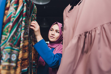 Arab woman in traditional Muslim clothes buys a new dress in an Oriental store.