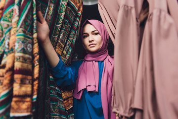 Arab woman in traditional Muslim clothes buys a new dress in an Oriental store.