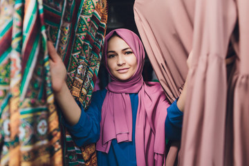 Arab woman in traditional Muslim clothes buys a new dress in an Oriental store.