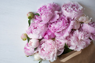 Bouquet of pink peonies in a paper bag on the table