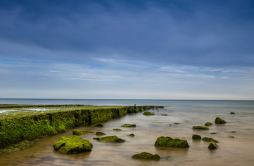 Flanked by tall cliffs, the lovely Porto de Mós Beach is like a long tongue of golden sand. At low tide the rocks at the end of the beach are exposed. In Lagos,Western Algarve coastline,  Portugal.