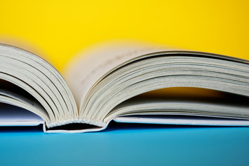An opened thick book or diary on a yellow and blue background. College or school library. Close-up