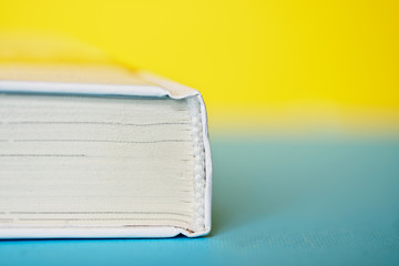 A thick white book or diary on a yellow and blue background. College or school science library....