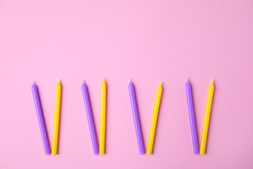 Bright birthday candles on pink background, flat lay