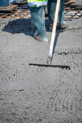 Construction worker spreading freshly poured concrete mix on the bridge with rake, repair sidewalk on bridge in Zagreb, Croatia