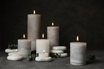 Composition with burning candles, spa stones and eucalyptus on grey table